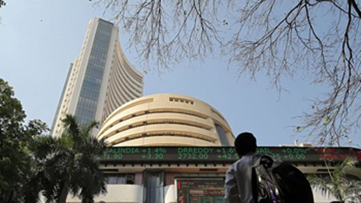 People look at a screen displaying the Sensex results on the facade of the Bombay Stock Exchange (BSE) building in Mumbai